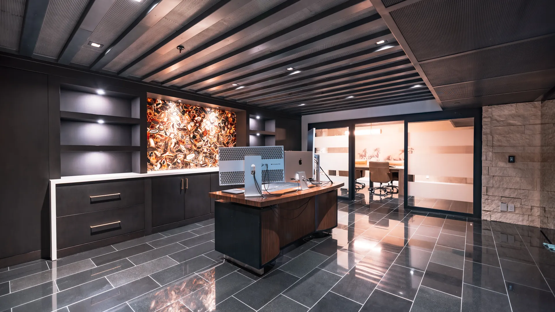 Dark corporate office with a backlit agate feature wall and polished stone floor